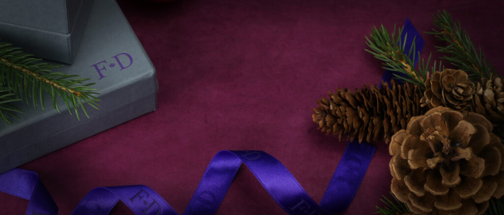 Purple ribbon and pine cone on a dark red background.