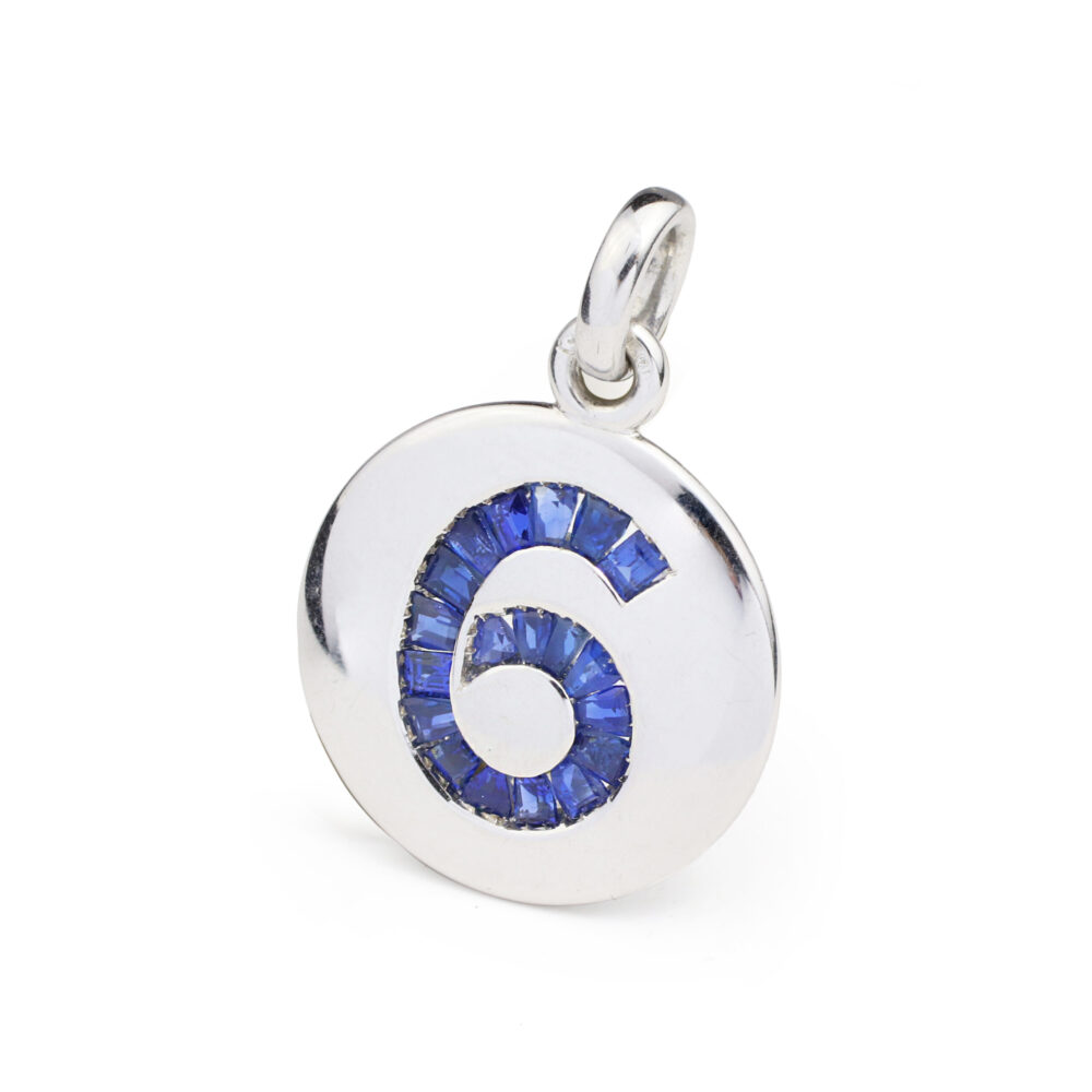 Designed a large round charm accented with a calibre cut sapphire set number 6, circa 1990
